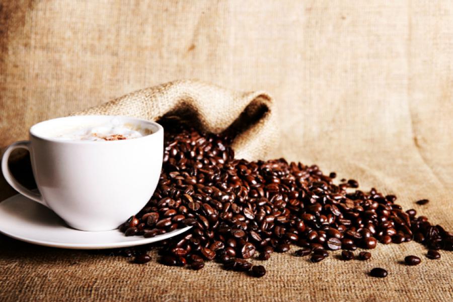 Tela de saco con café en una taza y granos de café encima.