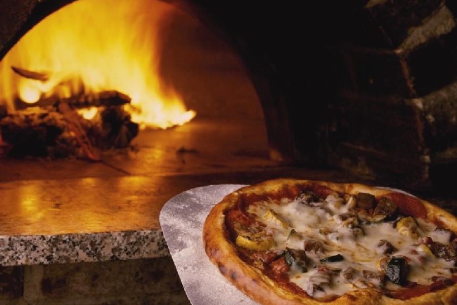 Horno con leña ardiendo y pizza recién hecha.