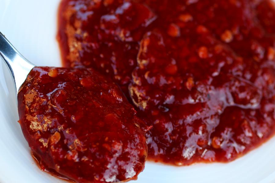 Sambal ulek en una cucharita y más salsa en un plato.