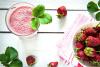Zumo de fresas con leche y fresas en una mesa de madera.