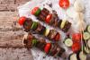 Brochetas de carne y verduras sobre madera.