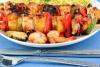 BRochetas de pollo y piña con su acompañamiento en un plato.