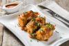 Un plato con tres calamares rellenos de arroz servidos con salsa de tomate en salsera.