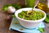 Pesto de espinacas en un recipiente de loza blanca, decorado con nueces.