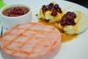 Un plato con una loncha de jamón asado, puré de patata y salsa de guindas.
