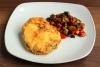 Una rodaja de merluza rebozada a la romana acompañada de verduras braseadas.