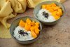 Dos cuencos con arroz con mango tailandés decorado con semillas de sésamo negro tostadas.