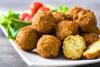 Un plato con varios falafel, uno de ellos cortado por la mitad y mostrando el interior.