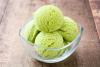 Un cuenco de vidrio con cuatro bolas de helado de matcha.