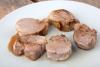 Cinco rodajas de solomillo de cerdo con un poco de salsa de vino tinto.