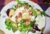 Un plato con ensalada de hojas variadas, queso azul, nueces y pera.